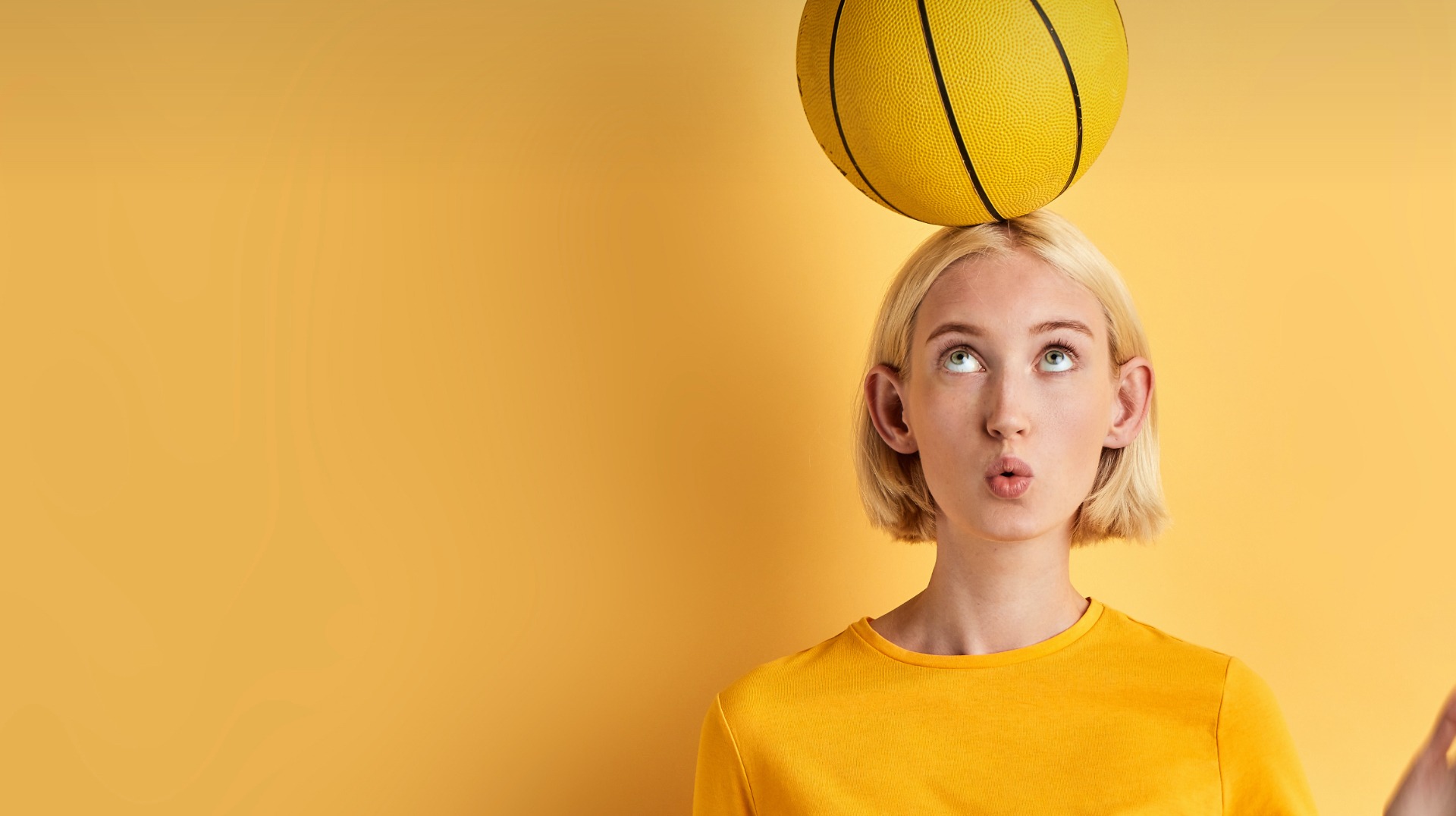 Jeune fille avec une balle de basket jaune sur la tête