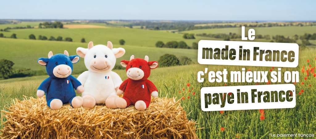 Trois vaches en peluche bleu, blanc et rouge posés sur une botte de foin